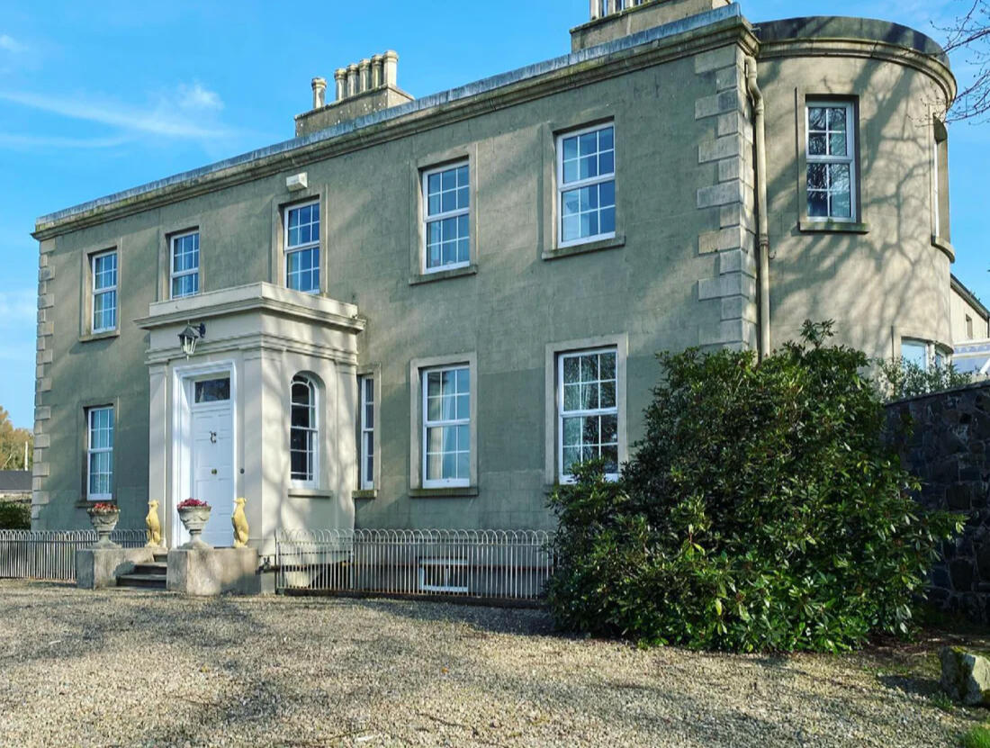 The front of Woodbank, a Georgian house with a white columned doorway