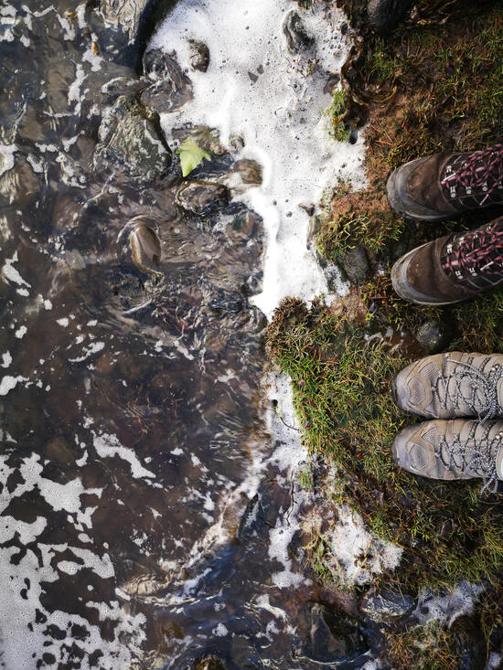 Walking boots beside the river among moss and stones